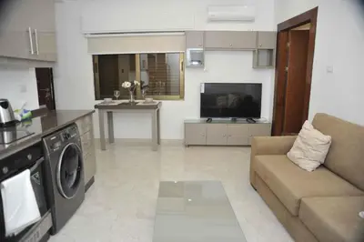 a living room with a couch and a kitchen at Amazing one Bedroom Apartment in Amman Elwebdah 2 in Amman