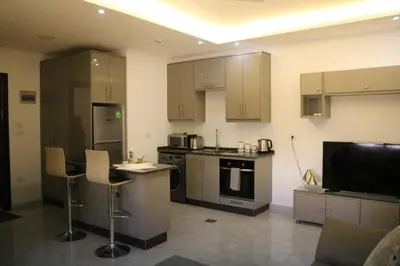 a kitchen with a counter and some chairs in a room at Amazing one Bedroom Apartment in Amman Elwebdah 5 in Amman