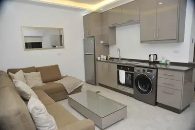 a living room with a couch and a kitchen at Amazing one Bedroom Apartment in Amman Elwebdah 6 in Amman