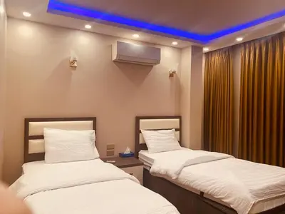 two beds in a room with a blue ceiling at Seven Days Hotel in Irbid