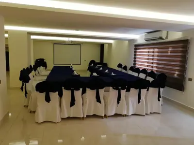 a conference room with tables and chairs and a screen at Seven Days Hotel in Irbid