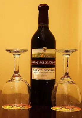 a bottle of wine and two glasses on a table at Mosaic City Hotel in Madaba