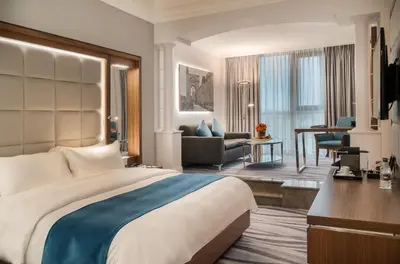a hotel room with a large bed and a living room at Landmark Amman Hotel & Conference Center in Amman
