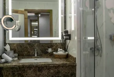 a bathroom with a sink and a mirror and a shower at Landmark Amman Hotel & Conference Center in Amman