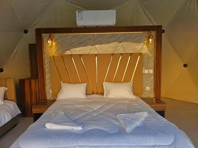 a large bed with a wooden headboard and white pillows at Luxury Color Camp in Wadi Rum