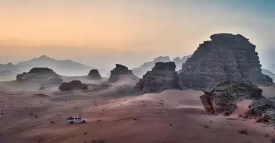 a white truck driving through a desert with large rock formations at Maraheb Luxury camp in Wadi Rum