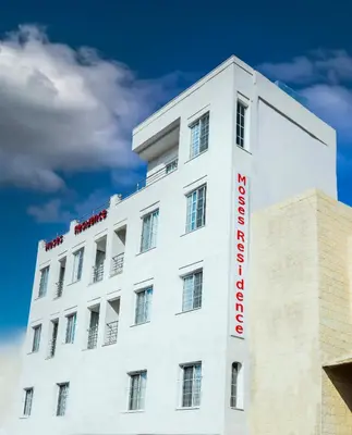 a white building with a red sign on it at Moses Residence in Wadi Musa