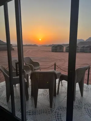 a group of chairs and a table with the sunset in the desert at Luxury Desert & Bedouin Adventure in Wadi Rum