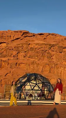 two women walking in front of a rock wall at Luxury Desert & Bedouin Adventure in Wadi Rum