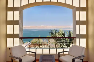 a room with two chairs and a view of the water at Dead Sea Marriott Resort & Spa in Sowayma