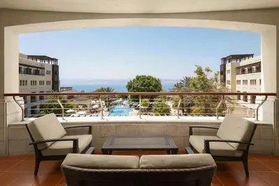a balcony with chairs and a table and a view at Dead Sea Marriott Resort & Spa in Sowayma