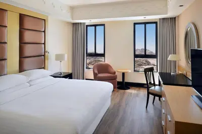 a hotel room with a large white bed and a desk at Petra Marriott Hotel in Wadi Musa