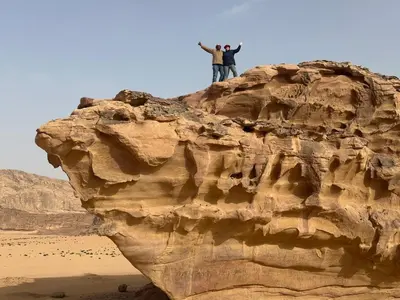 a man standing on top of a rock in the desert at Bubbles Desert Camp Jeep Tours in Wadi Rum