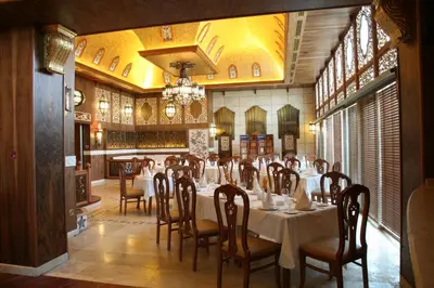 a dining room with tables and chairs and a chandelier at Le Royal Hotel - Amman in Amman