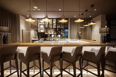 a kitchen with a bar with chairs and lights at Centro Mada Amman by Rotana in Amman
