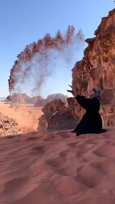 a woman sitting in a desert with a smoke at Shahrazad desert, Wadi Rum in Wadi Rum