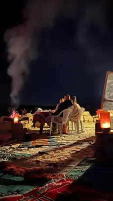 a group of people sitting in chairs on a beach at night at Omar Apartment in Wadi Musa