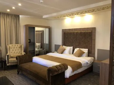 a hotel room with a large bed and a chair at AlQimah Hotel Apartments in Amman