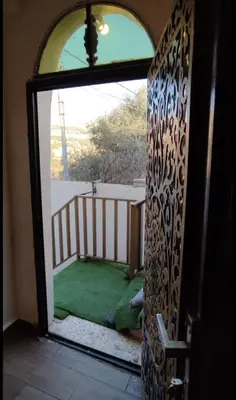 an open door to a balcony with a green yard at the prince apartment شقة الامير in Wadi Musa
