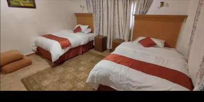 a hotel room with two beds and a chair at the prince apartment شقة الامير in Wadi Musa
