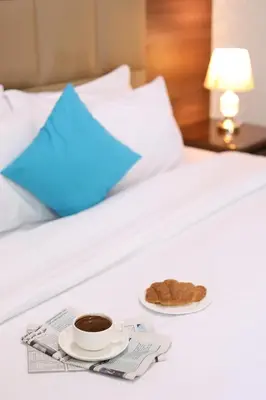 a tray with a cup of coffee and a cookie on a bed at The Castle Hotel in Amman
