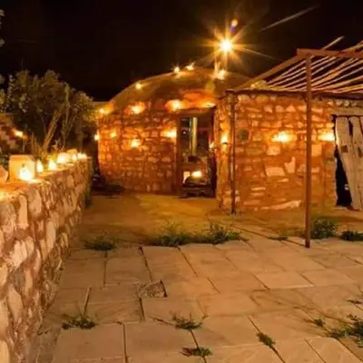 a stone wall in front of a stone building at night at Petra bedouin house in Al Ḩayy