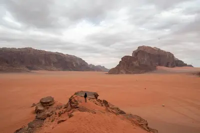 a person standing on a rock in the desert at Wadi Rum Nights in Wadi Rum