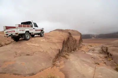 a truck driving on a dirt road in the desert at Wadi Rum Nights in Wadi Rum