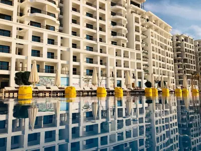 a building with chairs and umbrellas in a pool at Porto dead sea in Sowayma