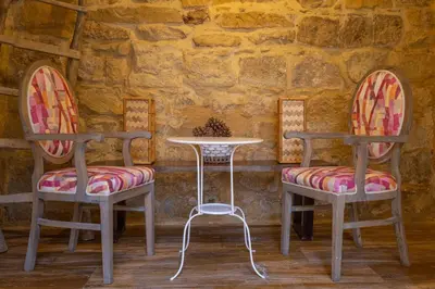 two chairs and a table in front of a stone wall at Jordan Heritage Madhafa in Al Salt