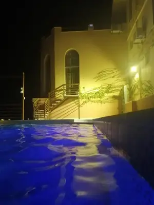 a building with a pool of snow in front of it at night at Sultana Farm - Private Pool Villa near Amman in Bayyūḑah