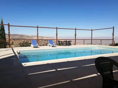 a swimming pool with two chairs and a table at Sultana Farm - Private Pool Villa near Amman in Bayyūḑah