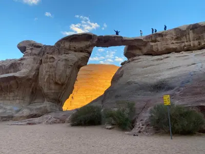 people standing on top of an arch in the desert at Abdullah desert trips in Wadi Rum