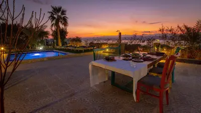 a table with a plate of food on it next to a pool at The Precious Villa in Sowayma