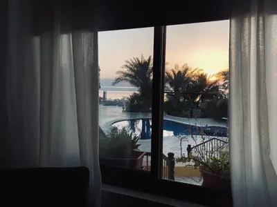 a window with a view of a pool and the ocean at The Precious Villa in Sowayma