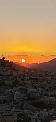 a sunset over a city with the sun setting at Cleopetra Hotel in Wadi Musa