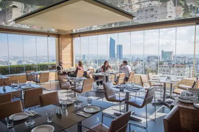 people sitting at tables in a restaurant with large windows at AlQasr Metropole Hotel in Amman