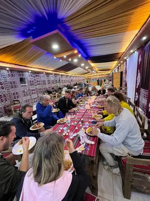 a group of people sitting at a long table eating food at orbit camp 2 in Wadi Rum