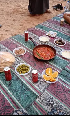 a table with food and drinks and a pan of food at Shakria Bedouin Life Camp in Wadi Rum