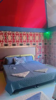 a bedroom with a bed with a red and green ceiling at Shakria Bedouin Life Camp in Wadi Rum