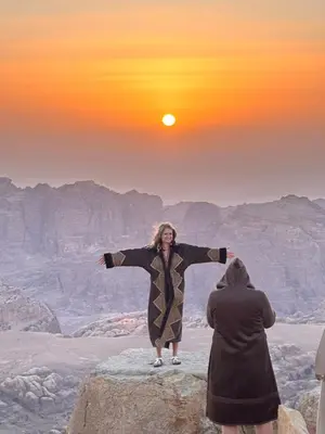 two women standing on a rock with the sun in the sky at Petra Desert Dream Hotel in Wadi Musa
