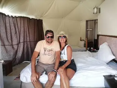 a man and a woman sitting on a bed at Lukasa camp Wadi Rum in Wadi Rum