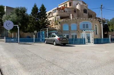 a car parked in front of a building with a blue fence at Celestia Boutique Inn in Jerash
