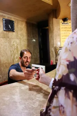 a man sitting at a table looking at his cell phone at Rana Palace in Amman