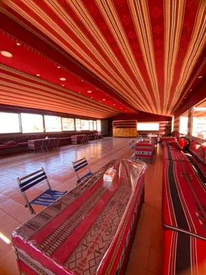 a large room with tables and chairs in a building at Wadi rum Moon Iight Camp in Wadi Rum