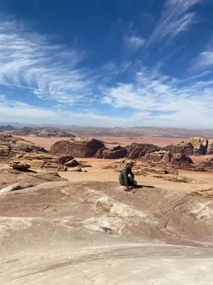 a man sitting on a rock in the desert at Wadi rum Moon Iight Camp in Wadi Rum