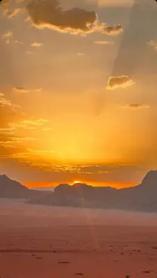 a sunset over the desert with mountains in the background at Wadi rum Moon Iight Camp in Wadi Rum