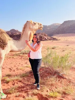a woman standing next to a camel in the desert at Wadi rum Moon Iight Camp in Wadi Rum