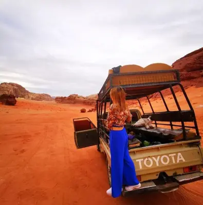 a woman standing in the back of a truck in the desert at moon city with jeep trips in Wadi Rum
