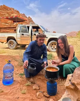 a man and a woman cooking food in a pot at moon city with jeep trips in Wadi Rum